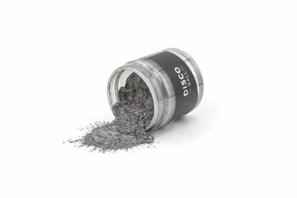 Sort mikropigment i lille gennemsigtig krukke med sort label, spildt kunstnerisk på hvid baggrund.