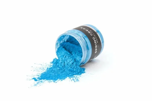 Lysturkisblå metallic epoxy pigmentspulver spredt fra åben krukke på hvid baggrund.